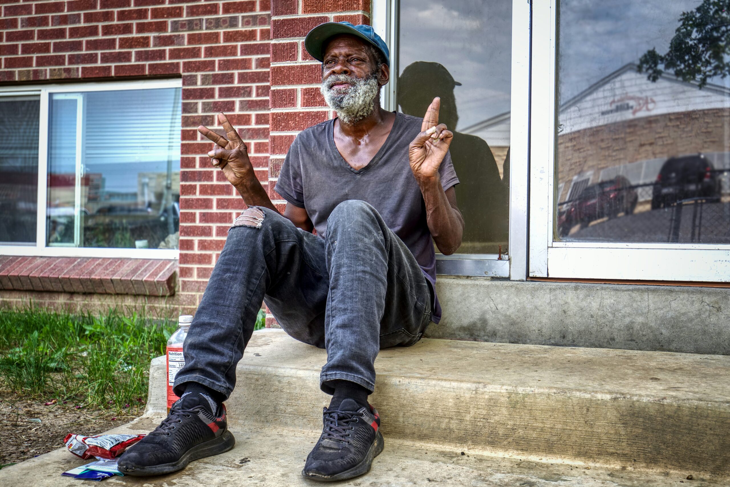Smiling bearded man sitting on steps gesturing