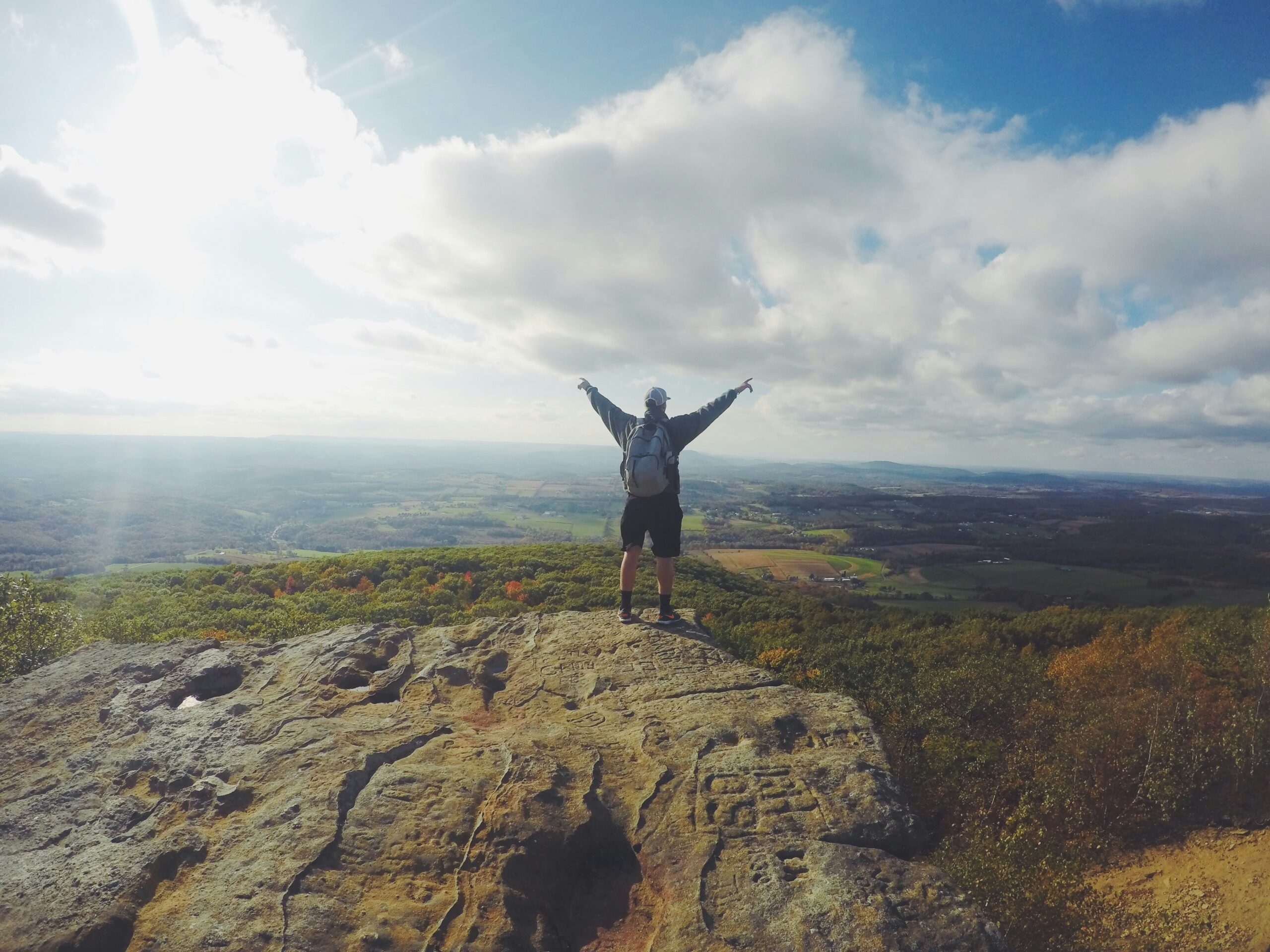 Hiker with arms raised on mountain overlook